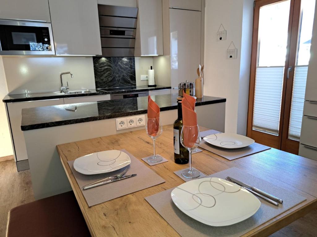 una cucina con tavolo in legno, piatti e bicchieri da vino di Apartment Alpina-3 by Interhome a Finkenberg