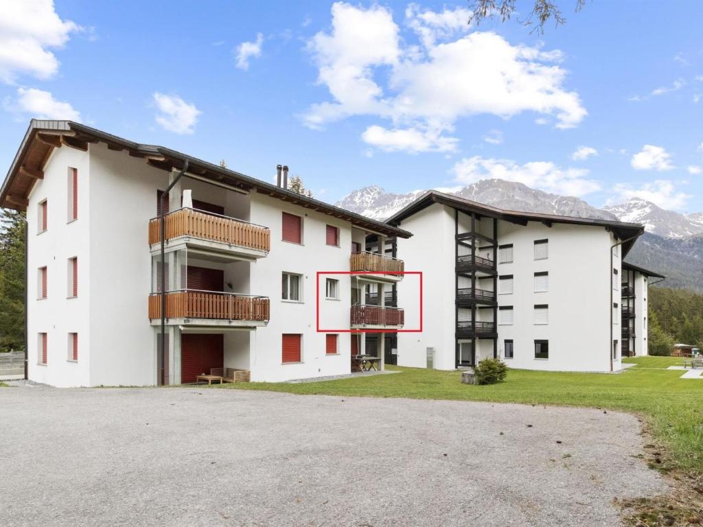 a large white building with mountains in the background at Apartment Auarara by Interhome in Lenzerheide