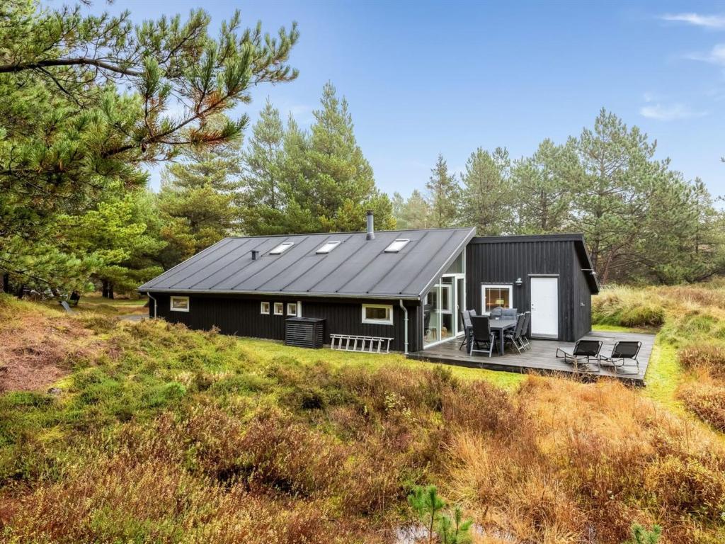 uma pequena casa preta numa colina com um deque em Holiday Home Emila - 2-2km from the sea in Western Jutland by Interhome em Bolilmark
