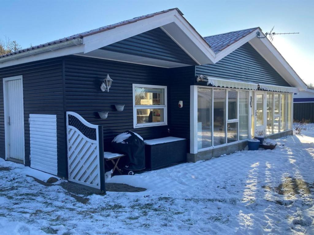 una casa negra con un porche en la nieve en Holiday Home Senja - 450m from the sea in NE Jutland by Interhome, en Hals