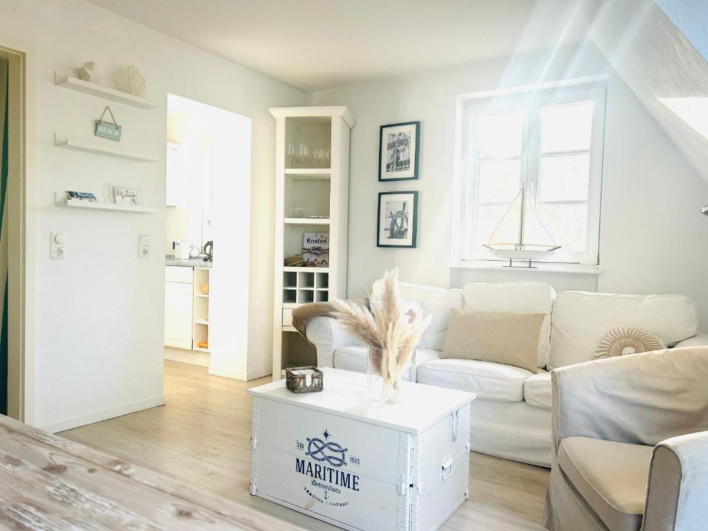 a living room with a white couch and a table at Maisonette-Fewo unter Reet, 50m zum Meer, Strandidyll Zingst in Zingst