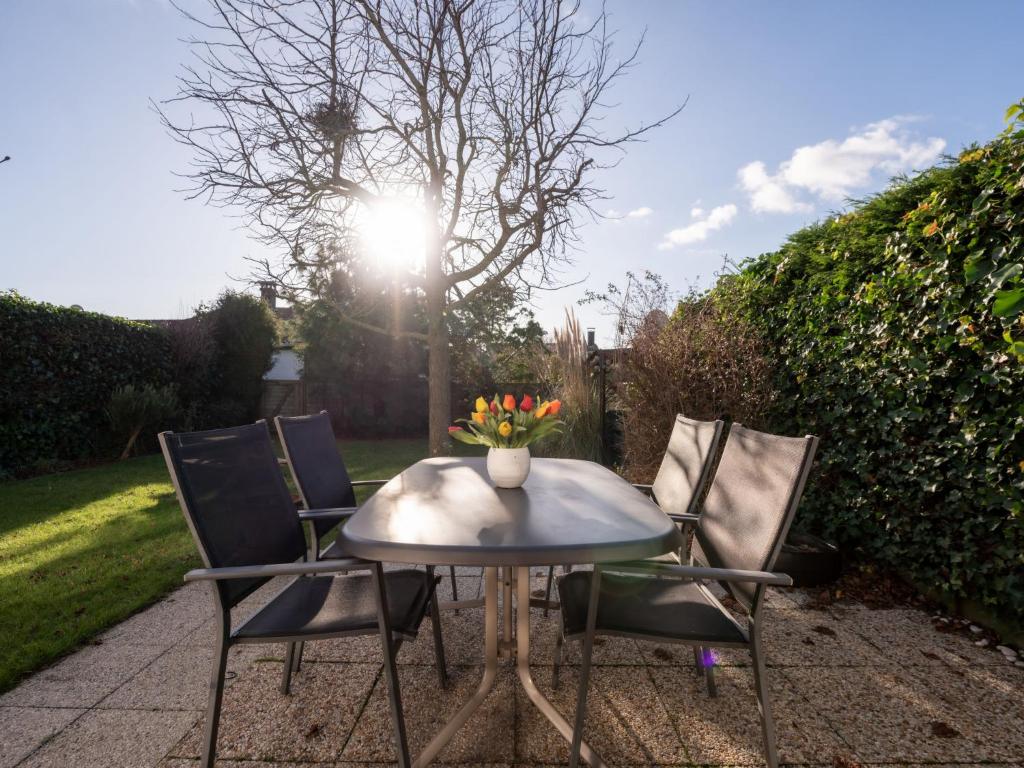 a table and chairs with a vase of flowers on it at Holiday Home zeewind by Interhome in Bredene