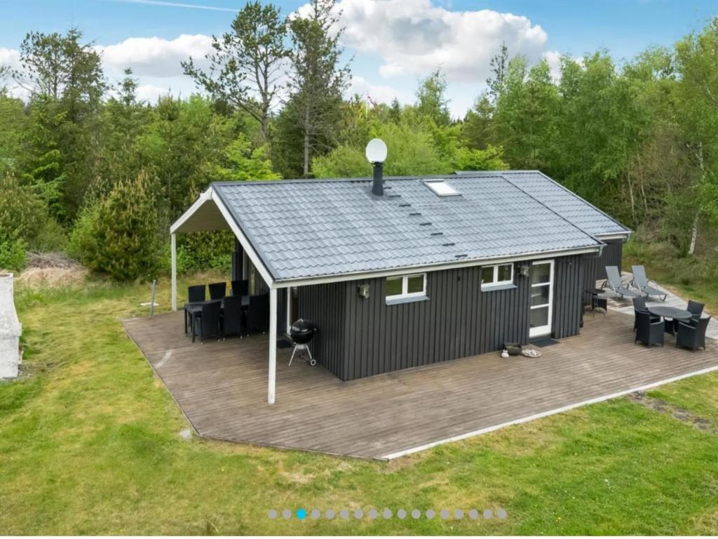 una casa con terraza y techo en Holiday Home Dwerg - 500m from the sea in NE Jutland by Interhome en Jerup