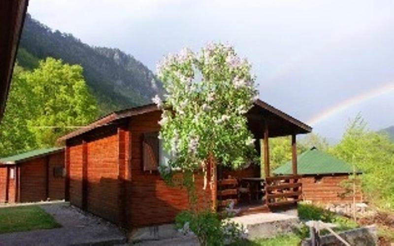 uma pequena cabana de madeira com um arco-íris ao fundo em Chalet Ravnjak at Tara Springs Park em Žabljak