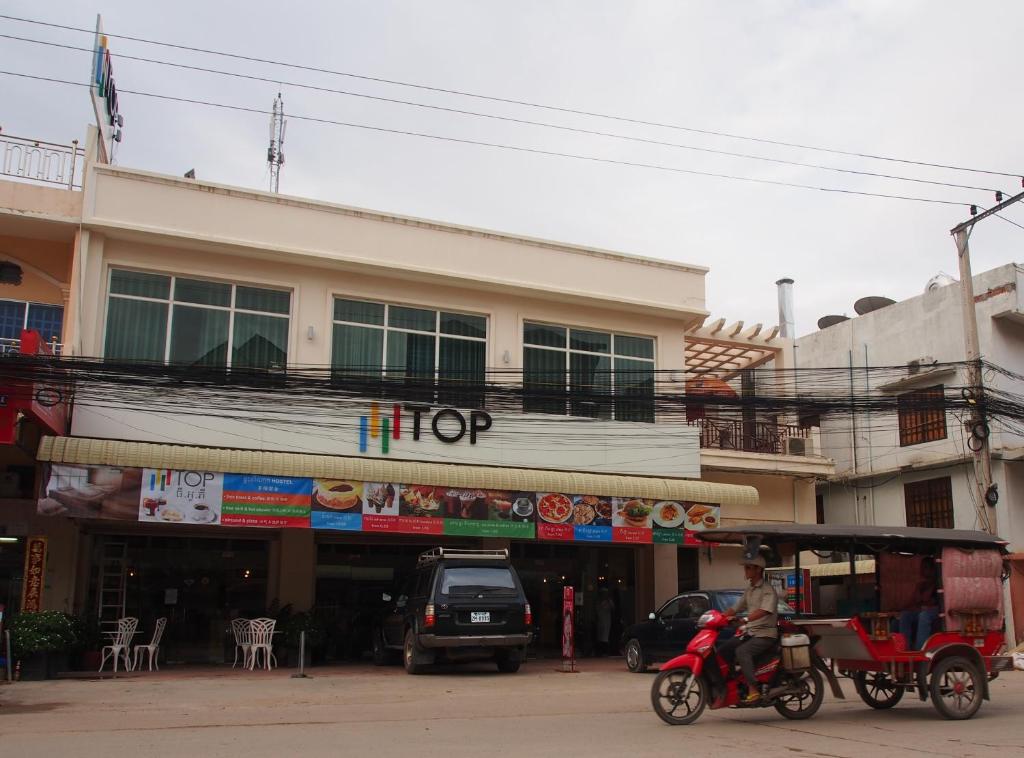 a man riding a motorcycle in front of a building at TOP Hostel in Phnom Penh