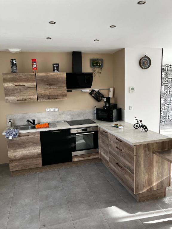 a kitchen with wooden cabinets and a black oven at Maison en travaux bientôt disponible in Oye-Plage