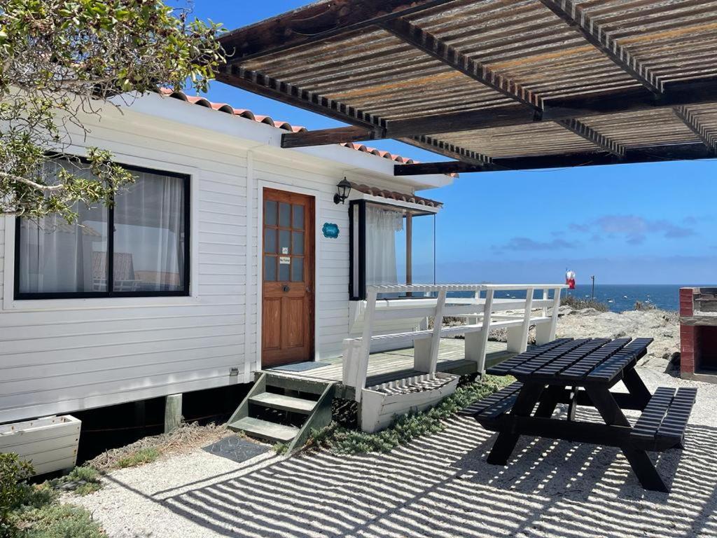a house with a picnic table on the beach at Cabañas & Camping Memoruz in La Higuera