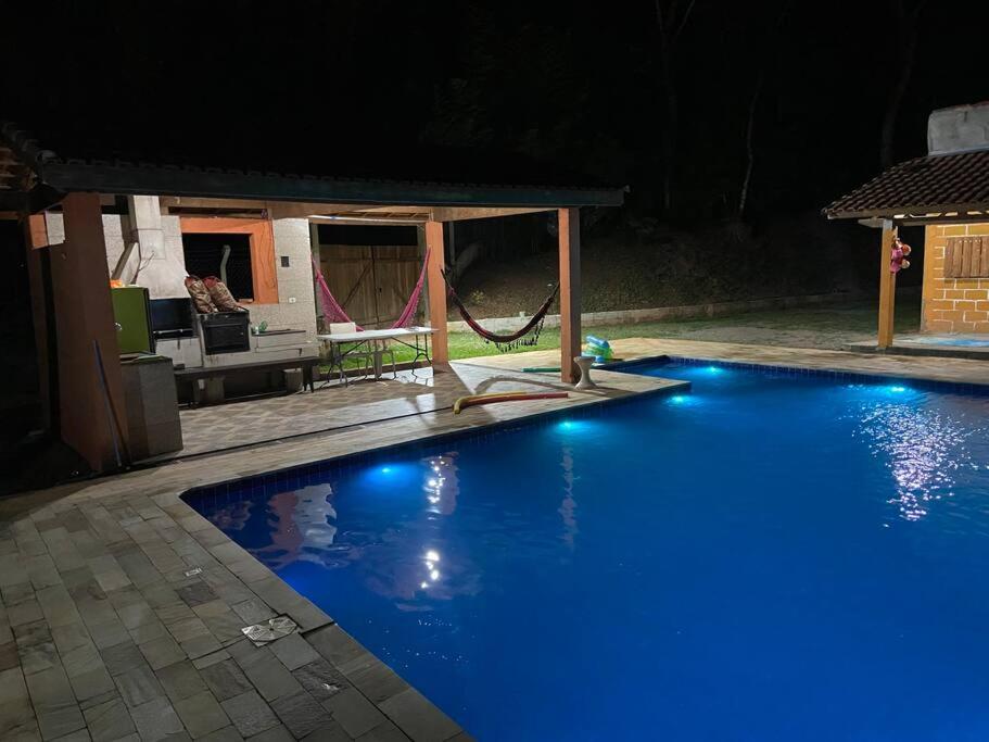 - une piscine avec des lumières bleues la nuit dans l'établissement Recanto da preguiça, à Igaratá