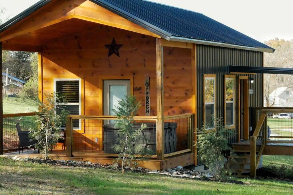 eine Blockhütte mit einer Veranda und einem Gamerleitdach in der Unterkunft Cozy Cabin - New Tiny Cabin with Hot Tub/Fire Pit in Sevierville