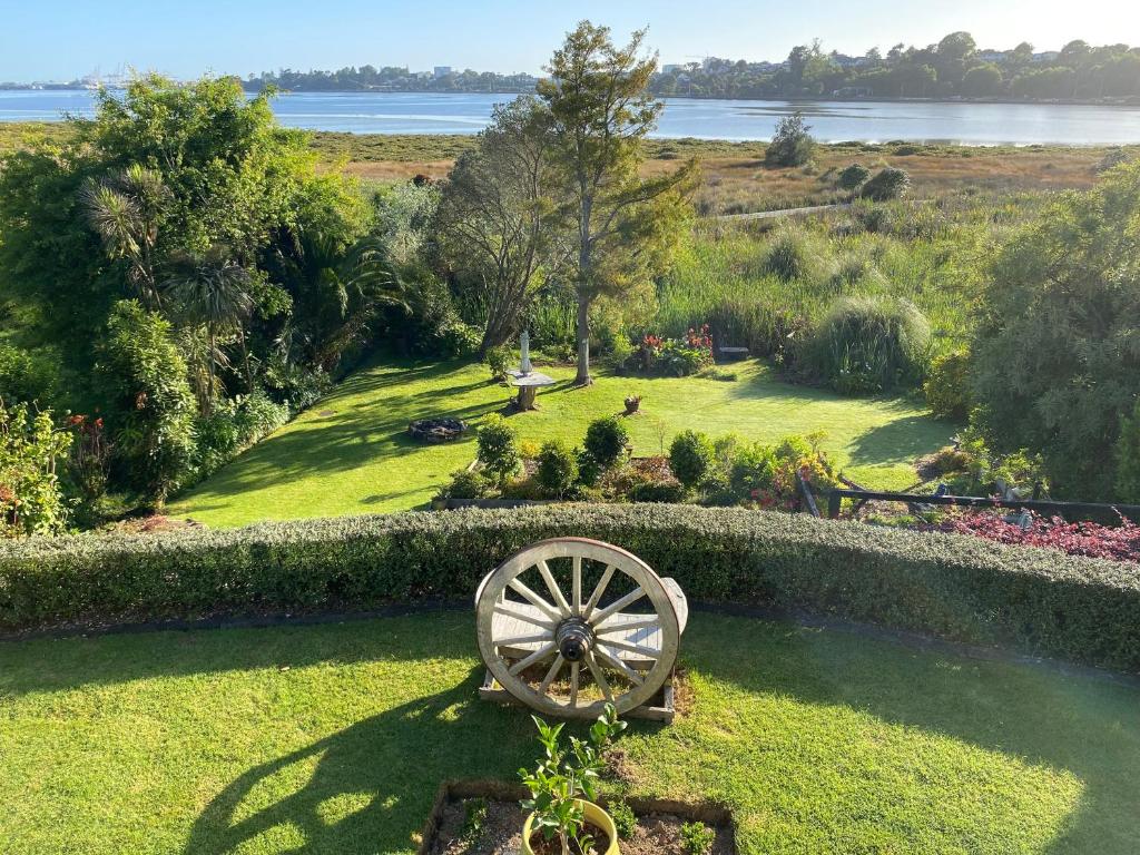 a garden with a wooden wheel in the grass at Churchill Oasis by the sea in Tauranga