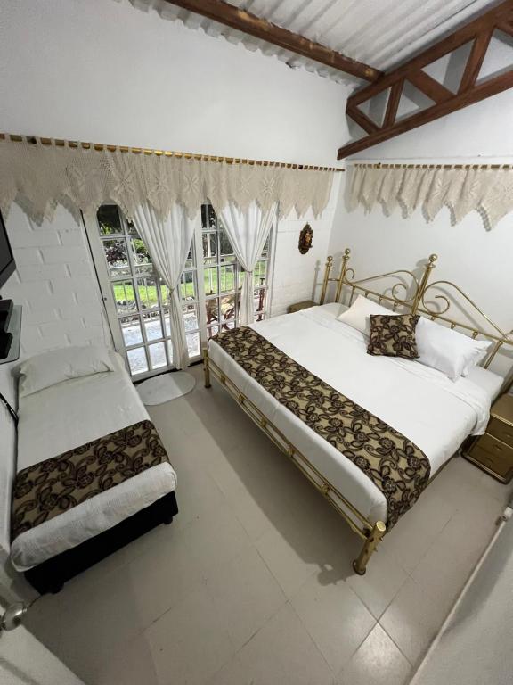 two beds in a room with white walls and windows at Finca Villa Antonella in Calarcá