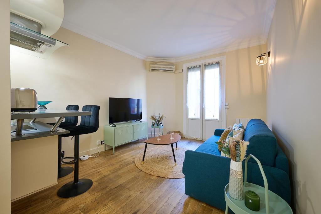 sala de estar con sofá azul y mesa en Le Refuge Parisien, en Montrouge