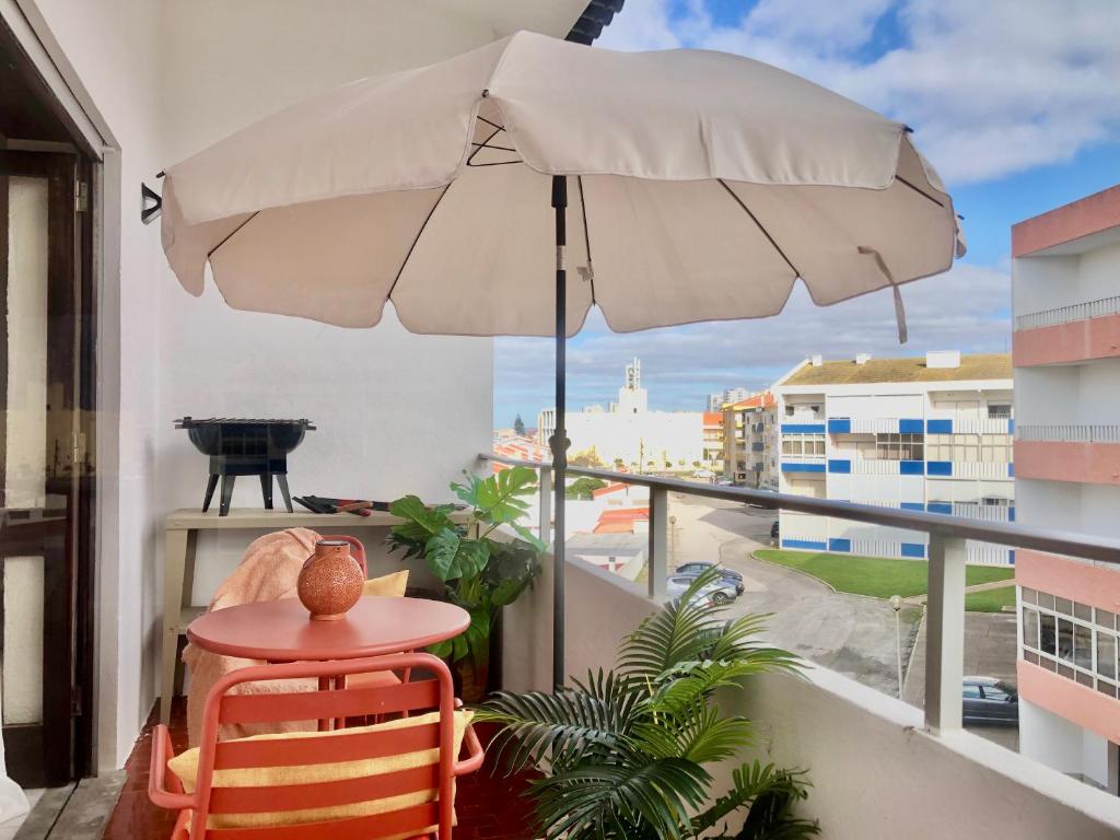 uma varanda com uma mesa e um guarda-chuva em Apartamento a 400 metros da praia Santa Cruz em Santa Cruz