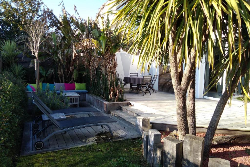une terrasse avec une table, des chaises et un palmier dans l'établissement Maison familiale entre parc et plage, à Saint-Nazaire