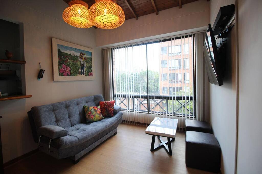a living room with a couch and a large window at Apartamento Cómodo en el Poblado in Medellín