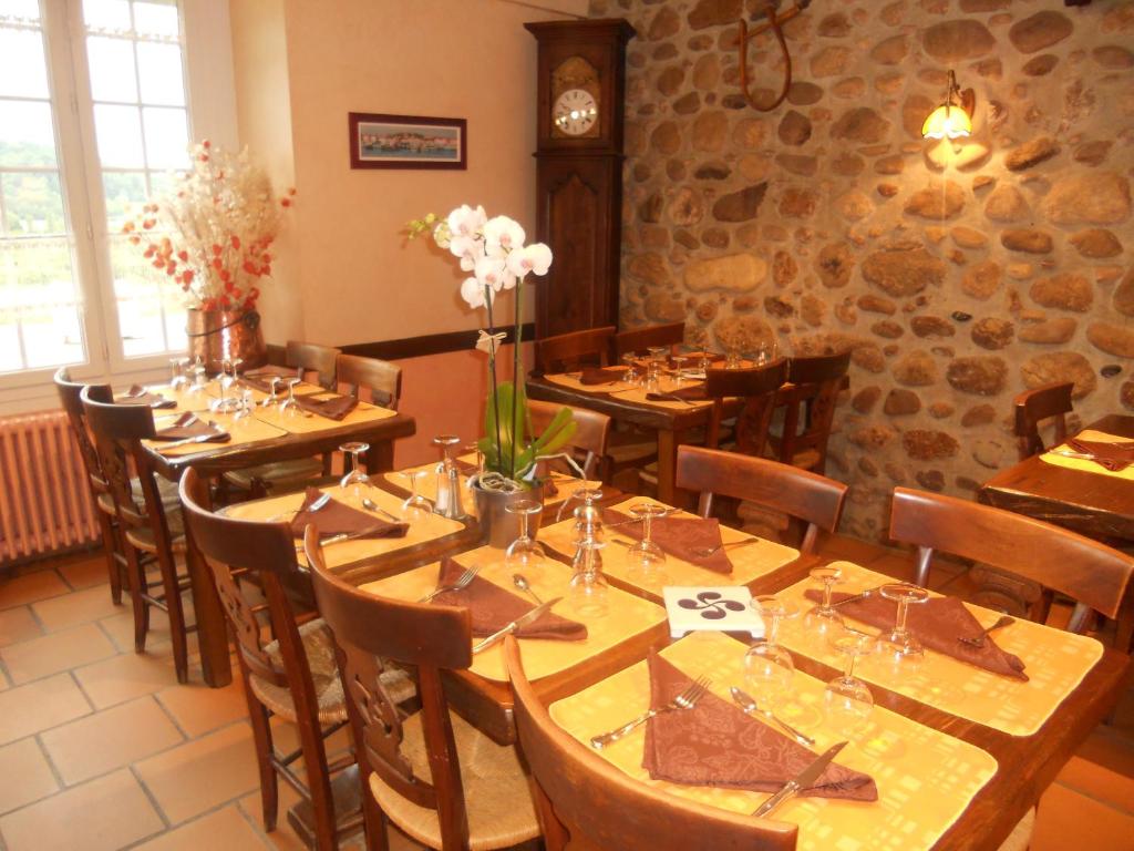 ein Restaurant mit Holztischen und -stühlen und einer Uhr in der Unterkunft Logis L'Auberge Basque in Ozon