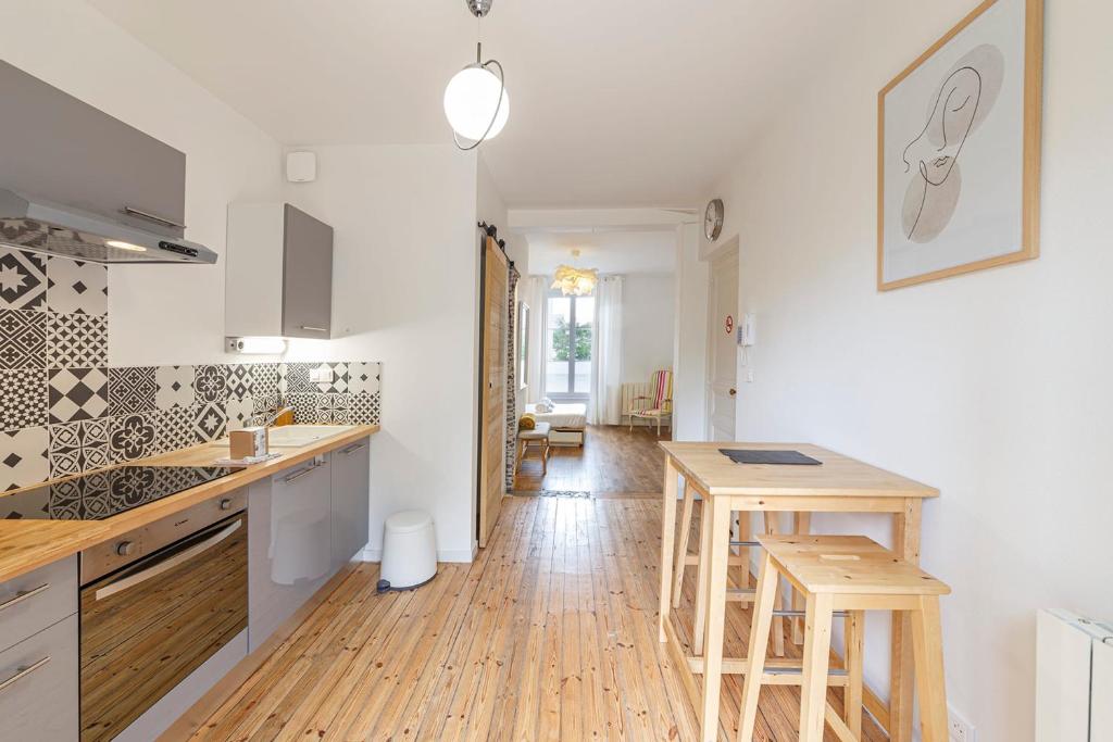 - une cuisine avec tabourets en bois et comptoir dans l'établissement Le Morphée - Appartement avec jardin, à Angers