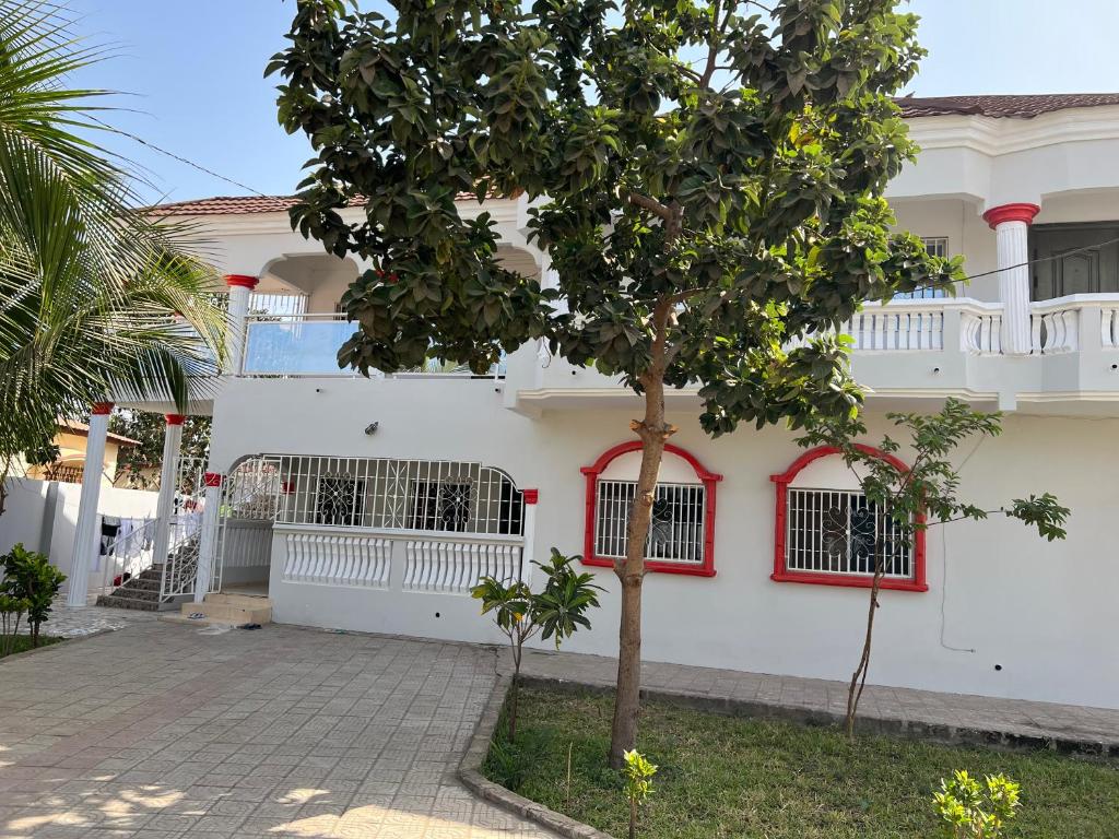 a white house with red windows and a tree at 3 bedrooms first story apartment in Sukuta
