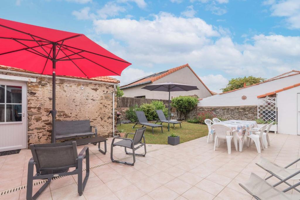 eine Terrasse mit Tischen, Stühlen und einem roten Regenschirm in der Unterkunft Birochère Maison lumineuse avec jardin in Pornic