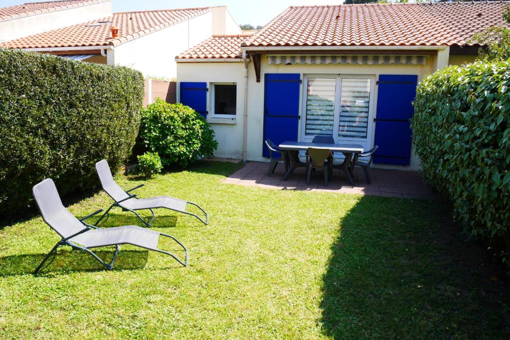 due sedie e un tavolo nel cortile di una casa di Maison résidentielle à 200 m de la mer a La Bernerie-en-Retz