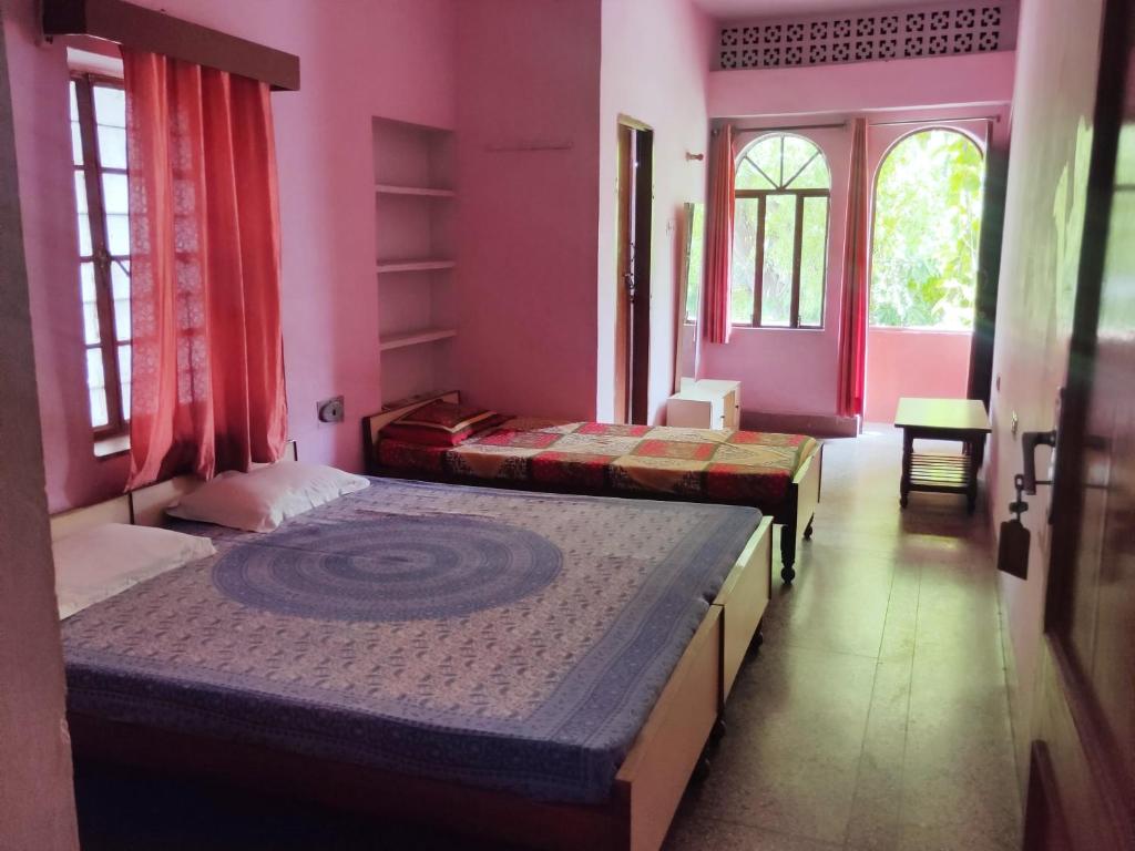 two beds in a room with pink walls and windows at JWALA JAIPUR in Jaipur