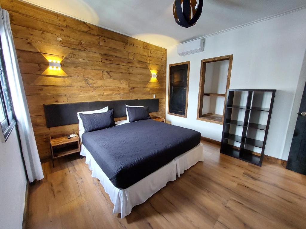 um quarto com uma cama e uma parede de madeira em Hotel Santiago Patio Bellavista em Santiago