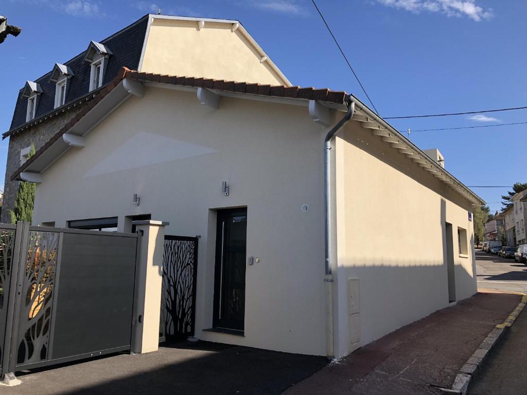 un bâtiment blanc avec une porte noire dans une rue dans l'établissement Apparts Watteau, à Limoges