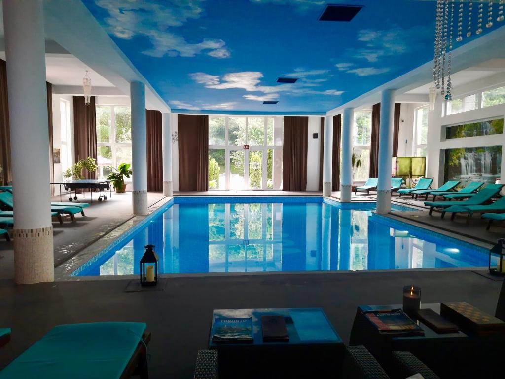 uma grande piscina num edifício com tectos azuis em Vila Roca Hotel and SPA em Valea Drăganului