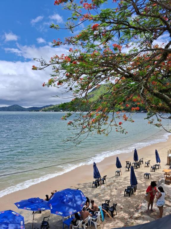 a beach with a bunch of chairs and umbrellas at Casa de praia de Ibicuí - RJ in Mangaratiba