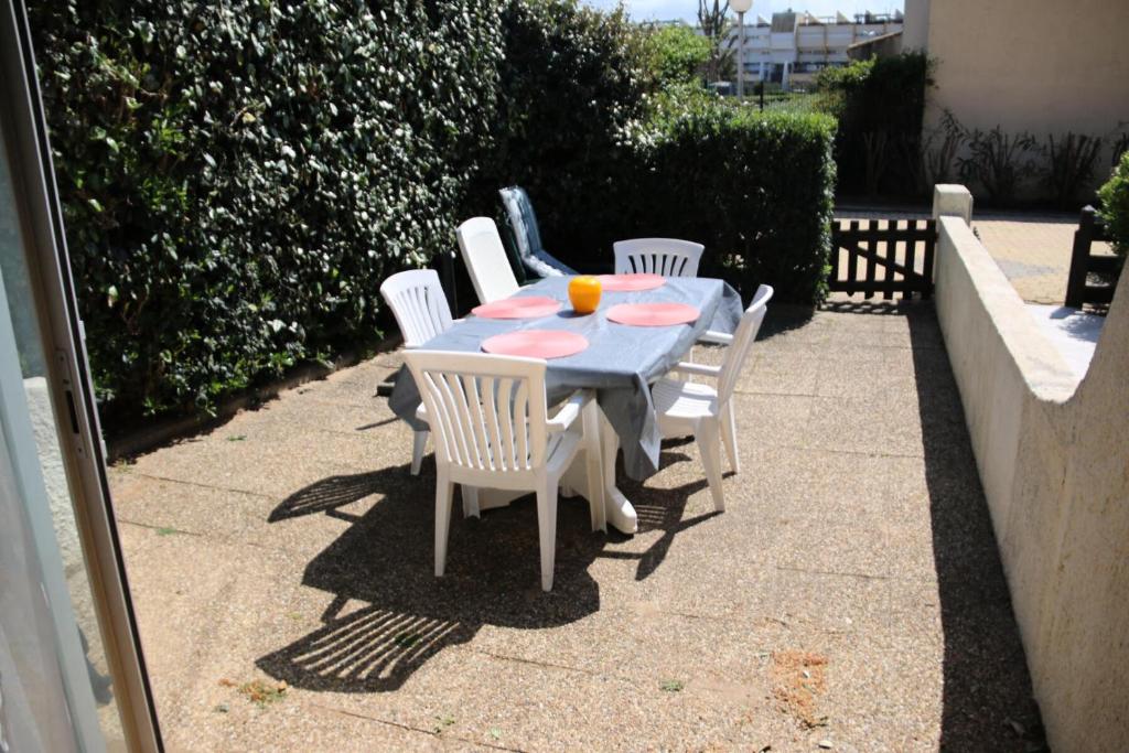 a table with white chairs and a blue table and chairsktop at Résidence HELIOVILLAGE - Maisons & Villas pour 4 Personnes 664 - Naturiste in Cap d'Agde