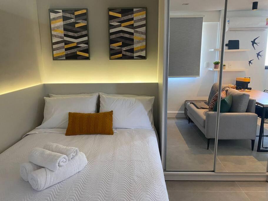 a bedroom with a bed with towels and a couch at Super compacto aconchegante. in Porto Alegre