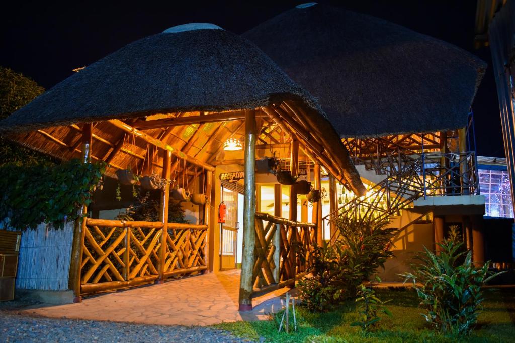 una casa de bambú con techo de paja por la noche en African Roots Gulu en Gulu
