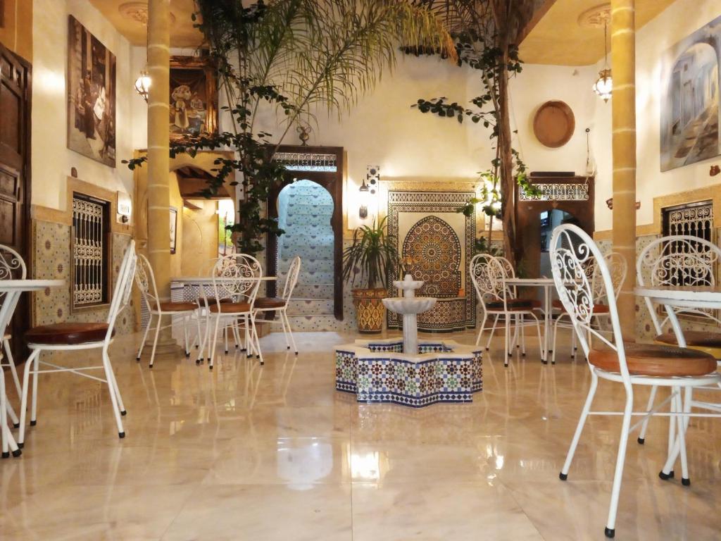 RIAD Dar Ouezzani في الرباط: غرفة طعام مع كراسي بيضاء وطاولة