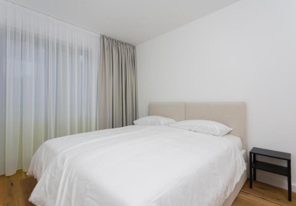 1 dormitorio con cama blanca y ventana en Deluxe Apartman Grey, en Bjelašnica