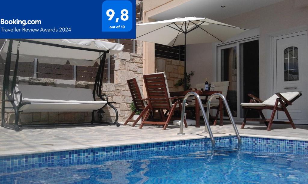 a swimming pool with chairs and a table and an umbrella at “Theeporto” Maisonette with pool in Gouves