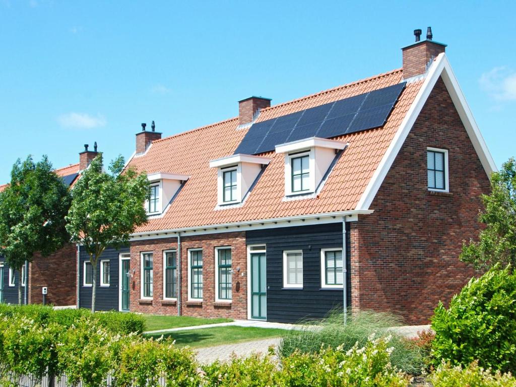 een huis met zonnepanelen op het dak bij Holiday home with whirlpool quiet area in Zeeland in Colijnsplaat