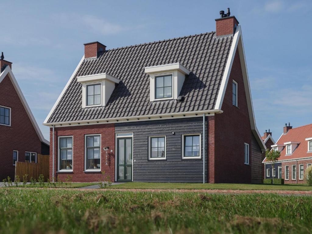 einem roten Backsteinhaus mit grauem Dach in der Unterkunft Detached family friendly villa in the Oosterschelde National Park in Colijnsplaat