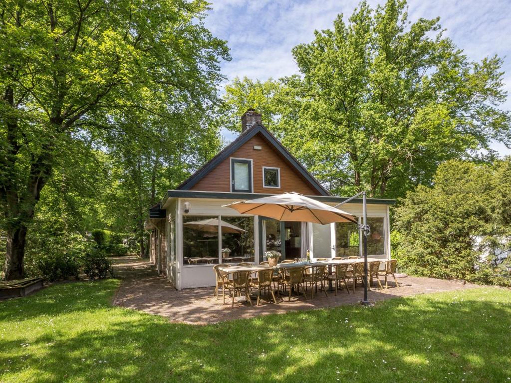 een huis met een tafel en een paraplu in de tuin bij Beautiful home with lots of privacy, in the forest in De Bult