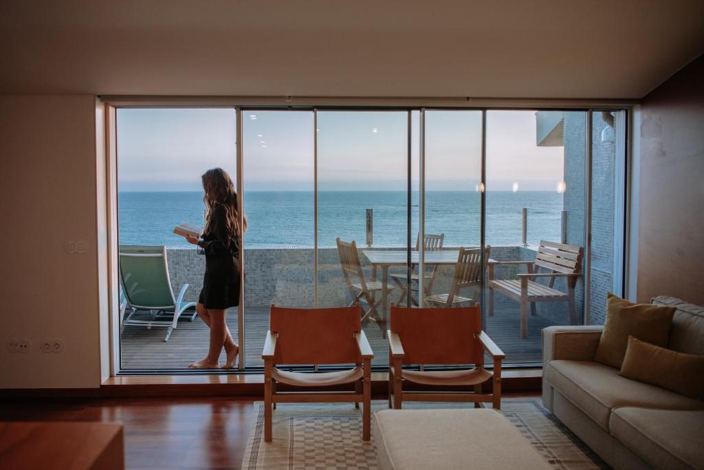 Una donna in piedi su un balcone che guarda l'oceano di Apartamento Luxo T3 Vista Mar-Tritão a Vila do Conde