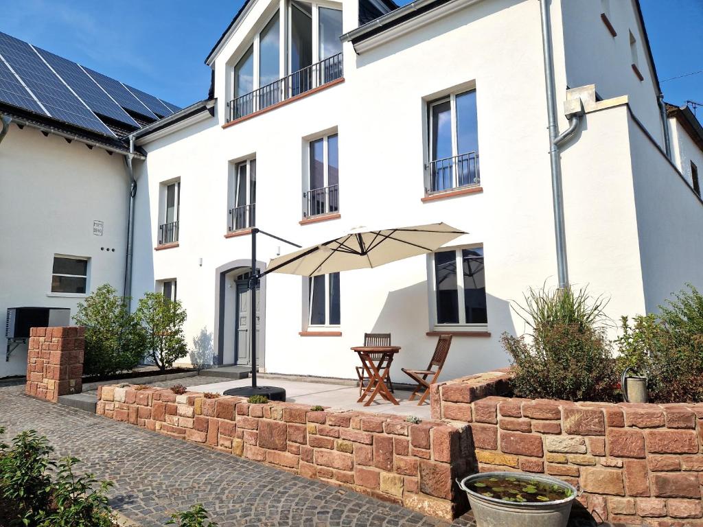 un patio con sombrilla frente a un edificio blanco en Ferienwohnung im ehemaligen Gesindehaus, en Welschbillig