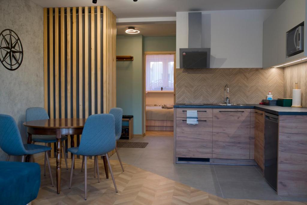 a kitchen with a table and blue chairs and a sink at Go2Krynica - Pod Jaworzyną in Krynica Zdrój