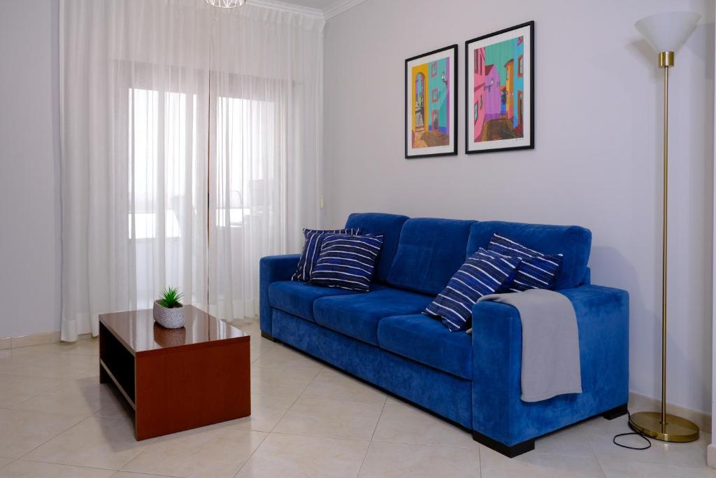 Un sofá azul en una sala de estar con una mesa. en Meriteluna Beach, en Parede