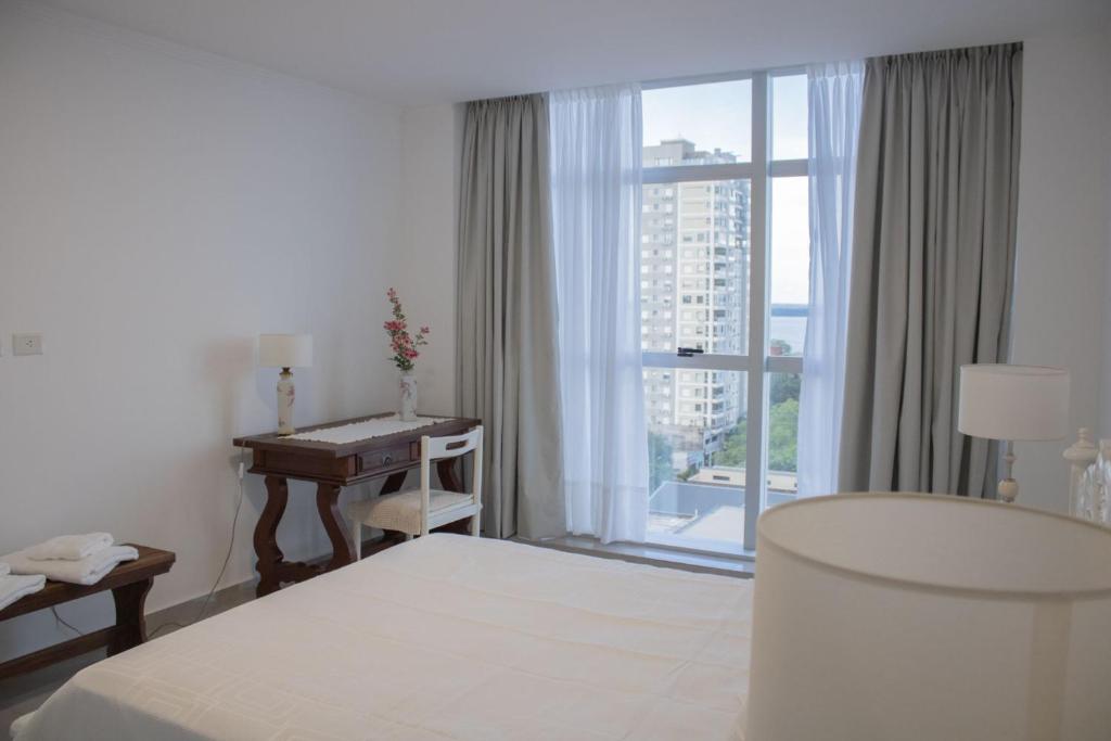 Habitación de hotel con cama, escritorio y ventana en IL Fiume - Exclusivo departamento Premium con Vista al Río en Posadas