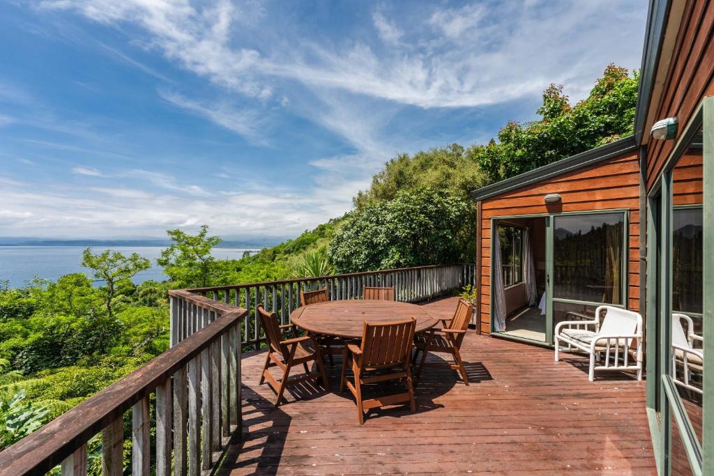 een houten terras met een houten tafel en stoelen bij Pukawa Paradise - Pukawa Holiday Home in Kuratau