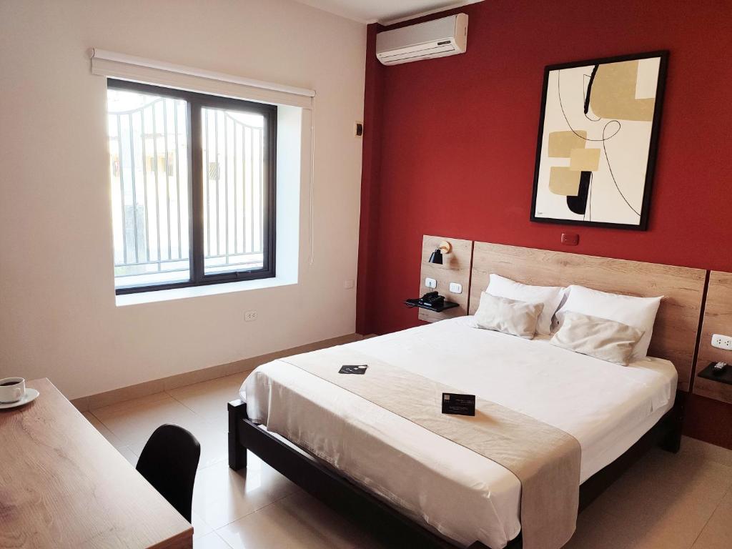 1 dormitorio con 1 cama grande y paredes rojas en Rua Hoteles Talara, en Talara