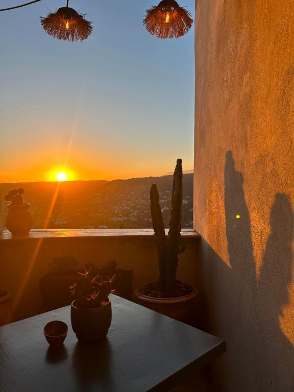 una puesta de sol vista desde una ventana con una mesa y un cactus en La Saint-Pauloise, en Saint-Paul-de-Vence