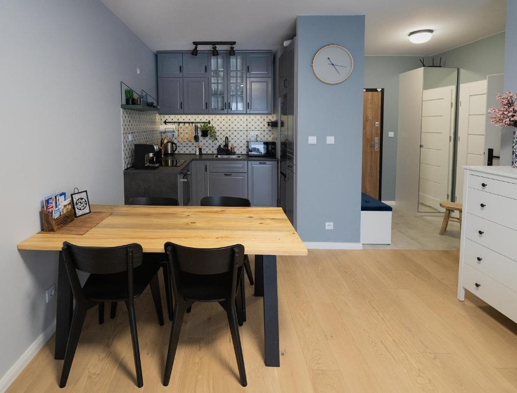 kuchnia i jadalnia z drewnianym stołem i krzesłami w obiekcie Blue Rooster Apartment. Cozy and quiet place to stay w Warszawie