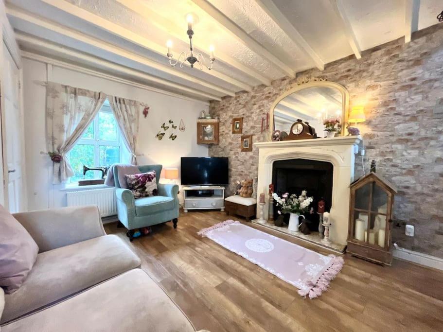 sala de estar con sofá y chimenea en Wisteria Cottage an authentic and enchanting cottage experience, en Aberdare
