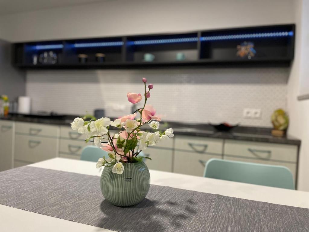 a green vase with pink flowers on a table at Green Oasis Garden in Šenčur