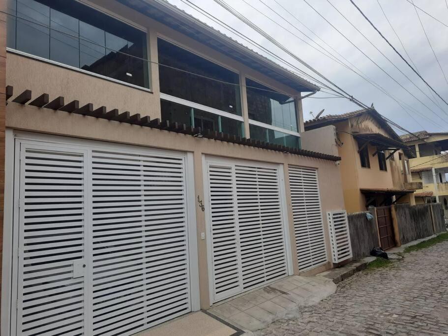 a house with white garage doors on a street at Casa de praia em Mar Grande-Ilha Itaparica in Vera Cruz de Itaparica